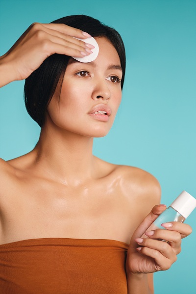 Asian brunette woman using facial cleanser