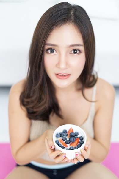 Asian woman eating fresh fruits nuts and yogurt