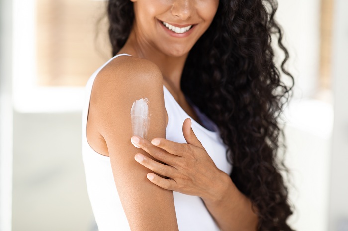 Body care of a woman applying moisturizer