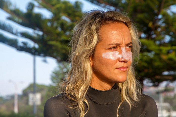 Girl surfer applying sunscreen on face