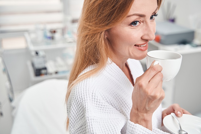 middle aged woman having coffee break in a beauty clnic before getting glutathione injections