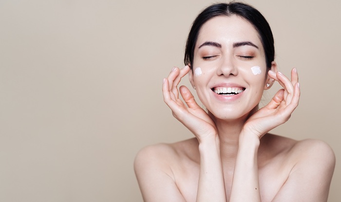 Pretty woman applying cream on face