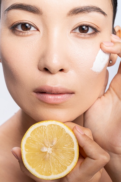 Woman applying facial cream with lemon extract