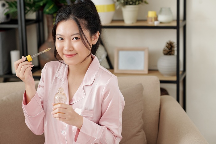 Woman applying vitamin c serum on face