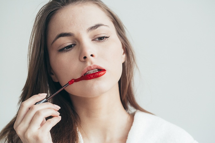 Woman falsely applying lip stick on her lips