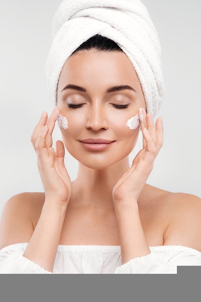 Woman using facial moisturizer cream on face