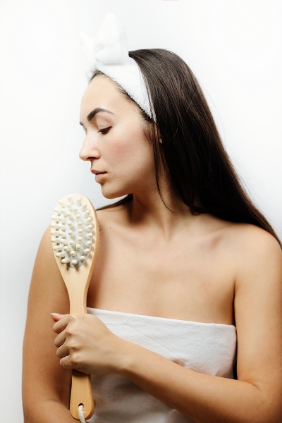 Woman using massage brush for peeling and exfoliation
