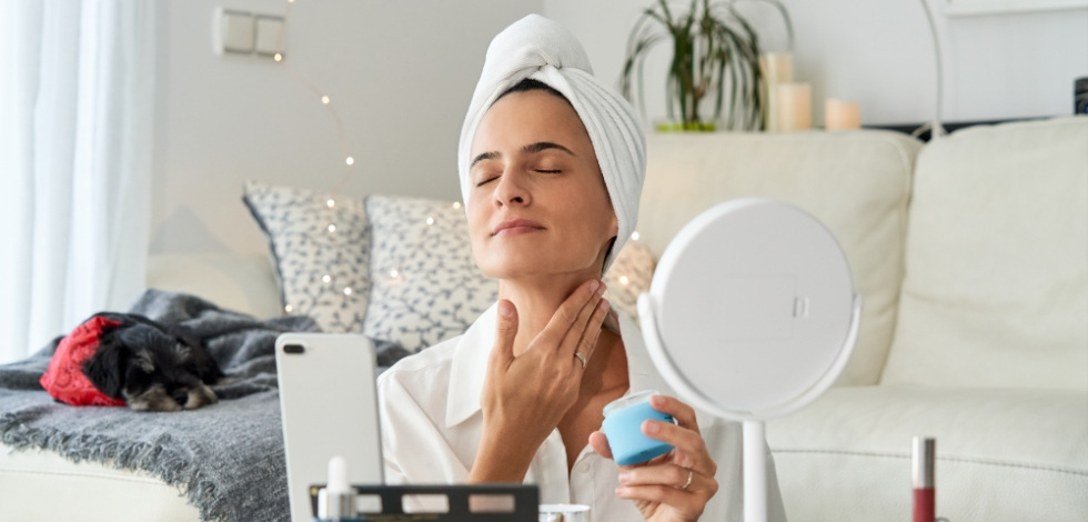 happy woman applying lotion to neck