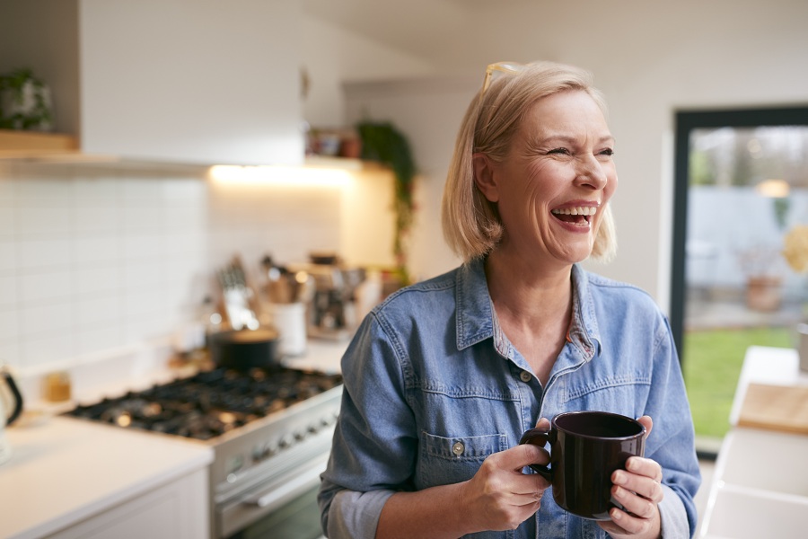 laughing mature woman at the kitchen with visible smile lines on her face