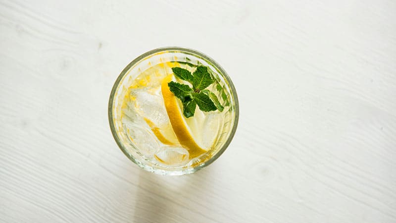 A glass of water with lemon and mint leaves 